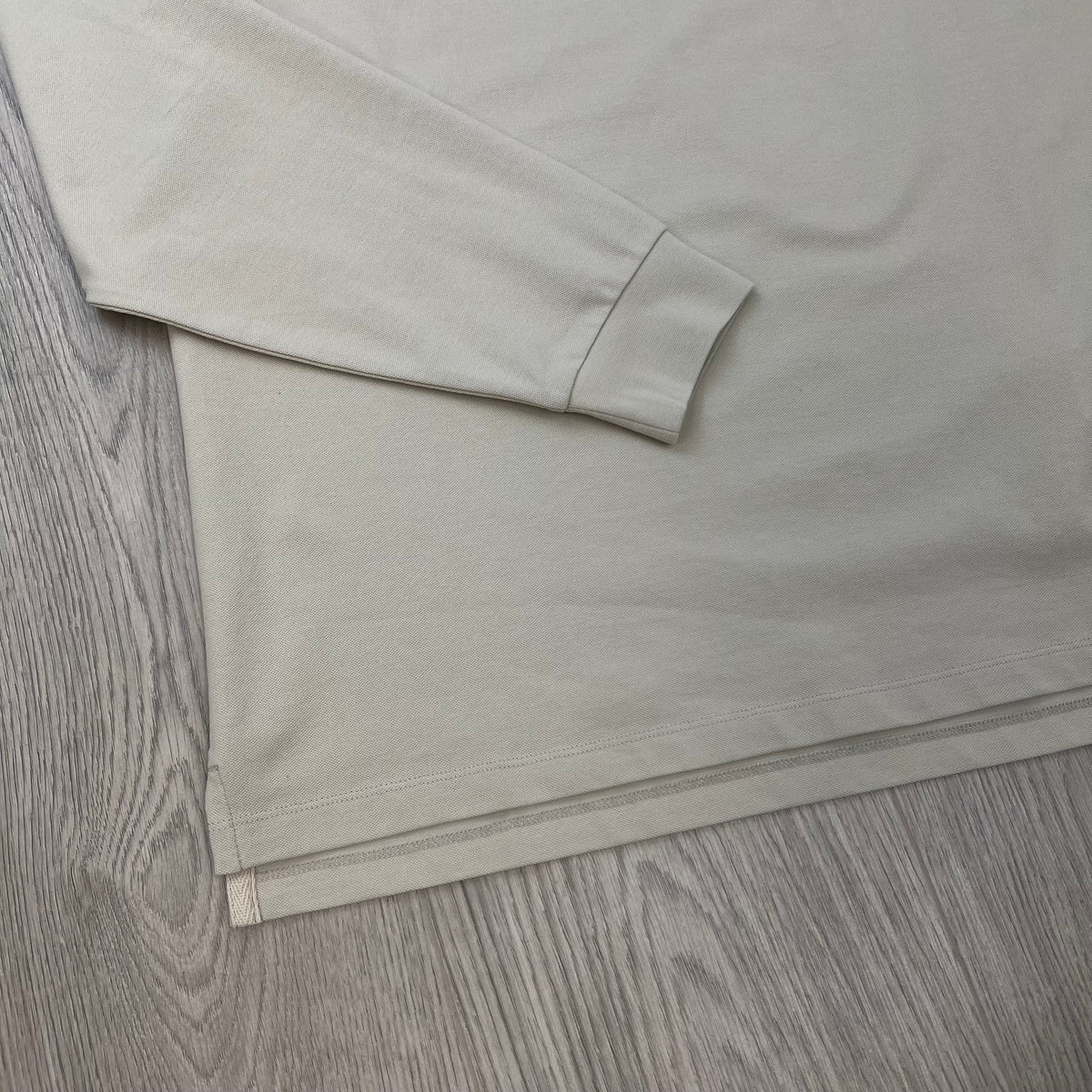 Close up view of the ribbed cuffs on a CP Company Long Sleeve Stretch Piquet Polo Shirt in Silver Birch.