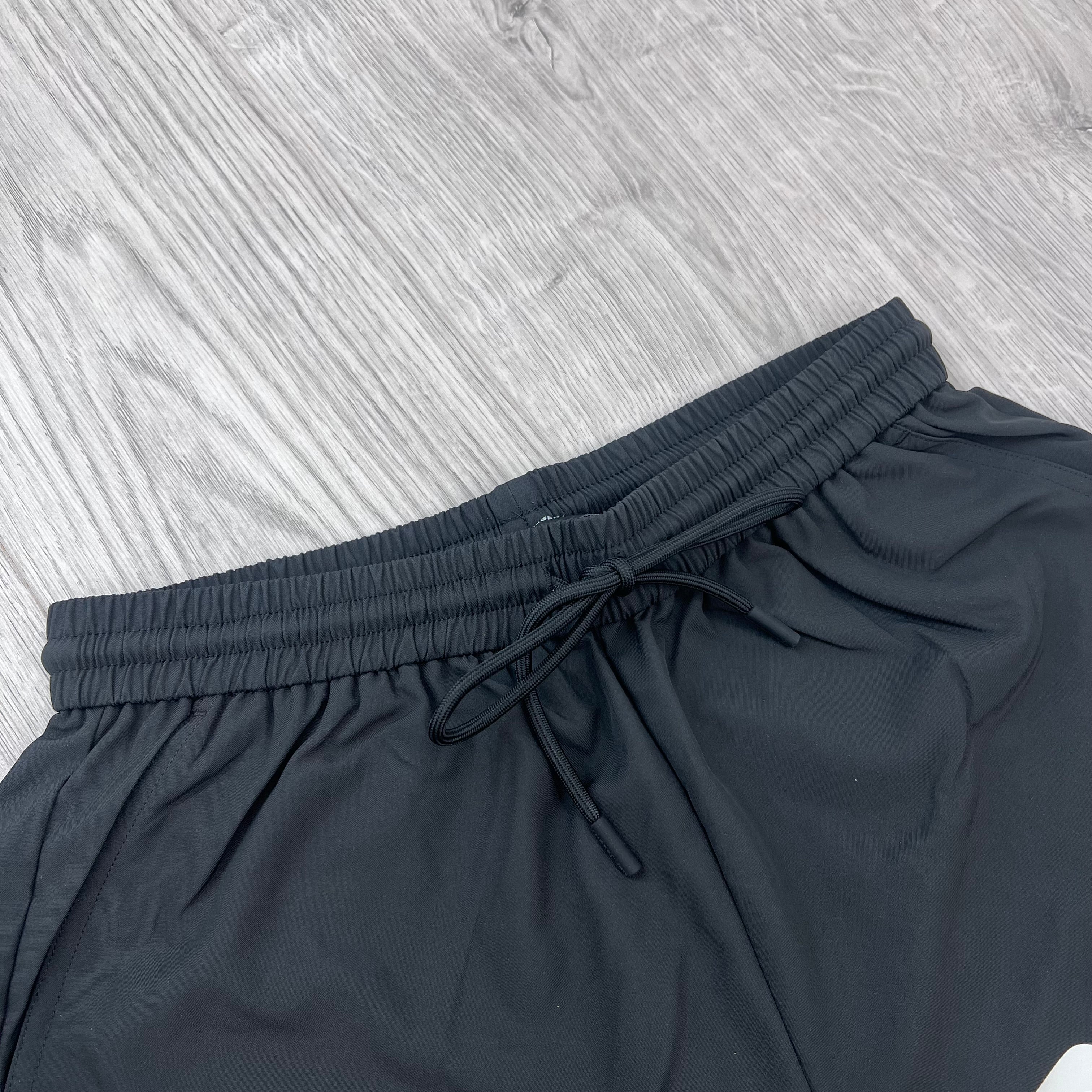 A close up view of the elasticated waistband on the Represent Swim Shorts in Black.