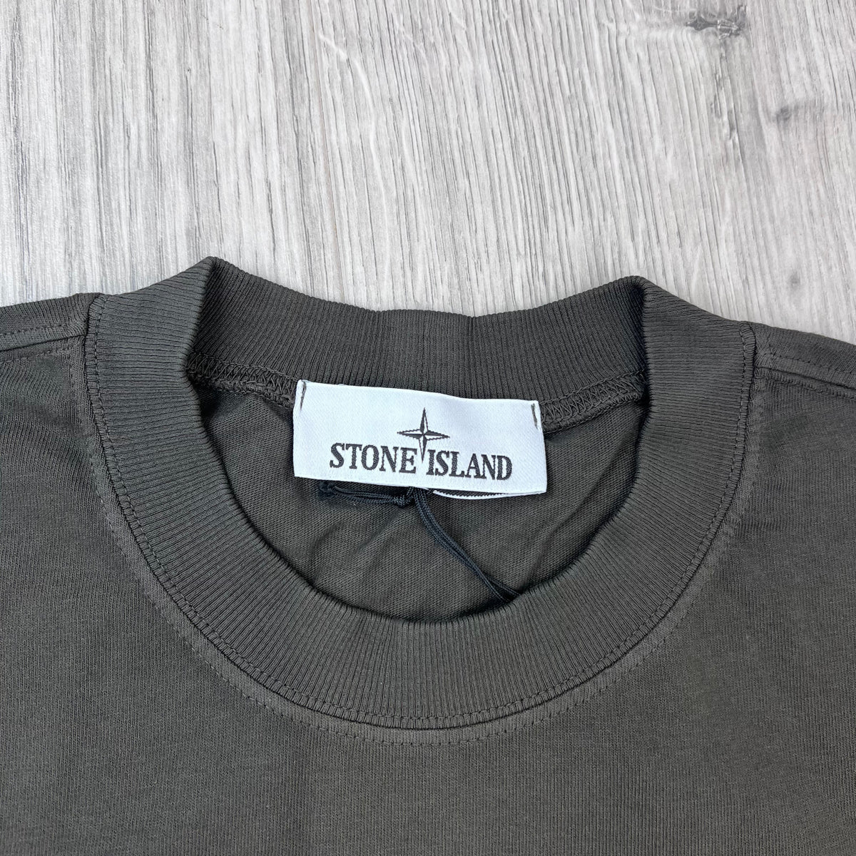 A close up view of the crewneck collar on a Stone Island Combed Organic Patch T-Shirt in Coal Grey. 