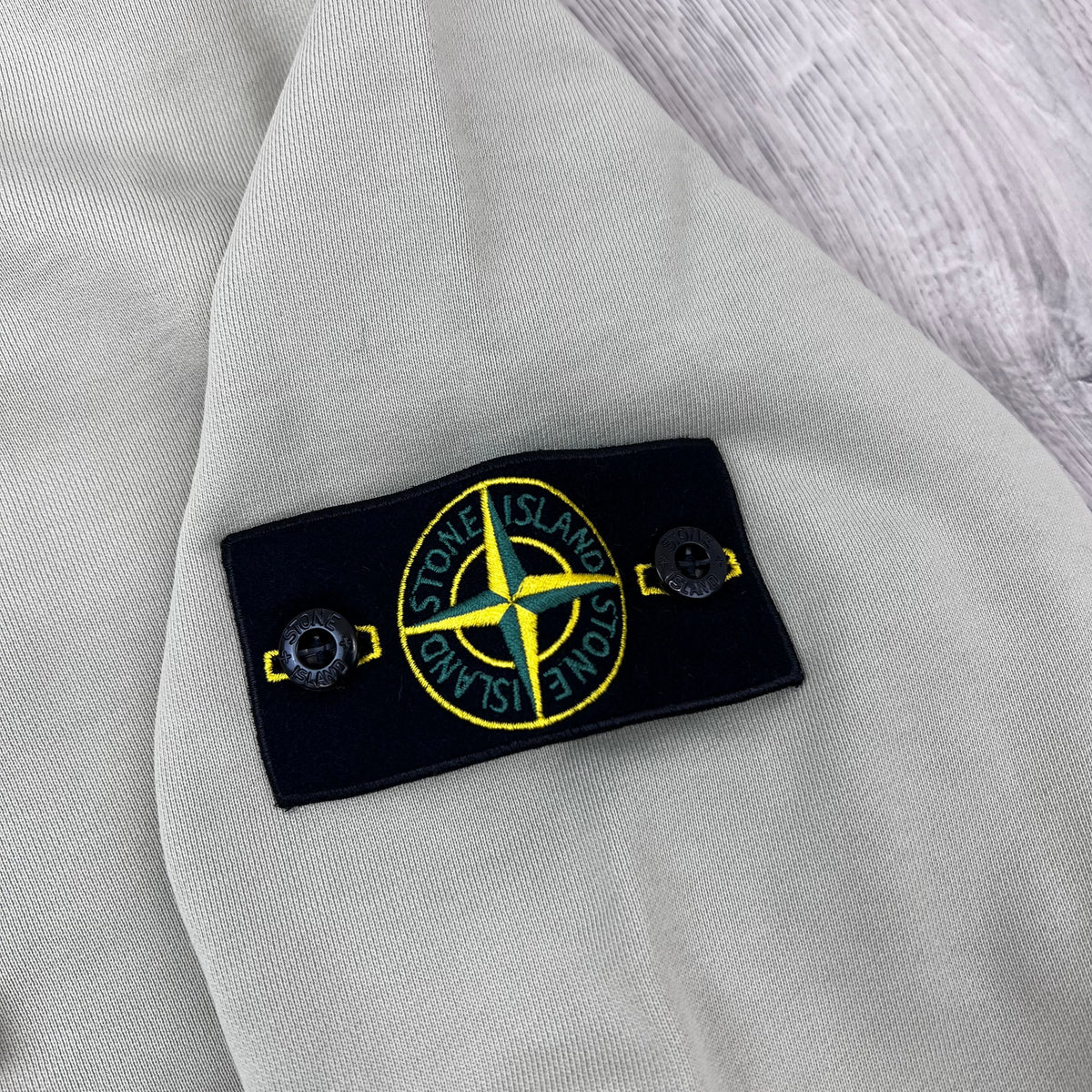 A close view of the badge logo on a Stone Island Pullover Hoodie in Sand. 