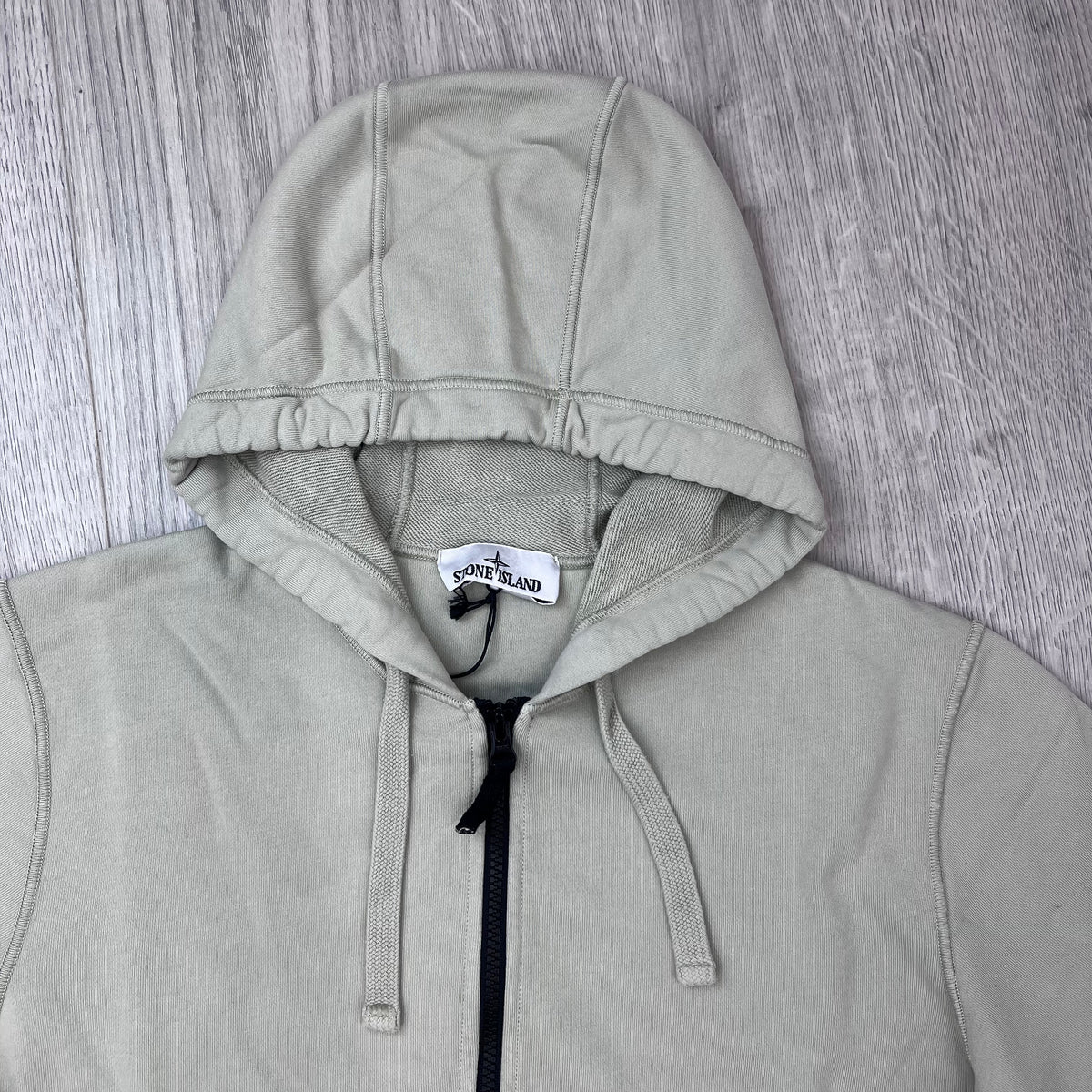 A close up view of the hood and drawstring on the Stone Island Zip Hoodie in Sand. 